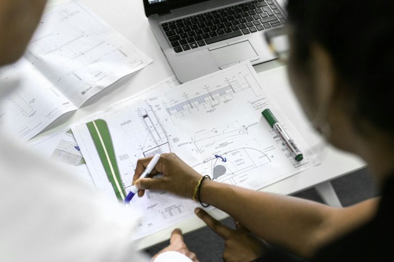 Schallpegelmessungen health & safety ehrl Zwei Personen stehen am Schreibtisch und lesen zusammen eine technische Zeichnung.