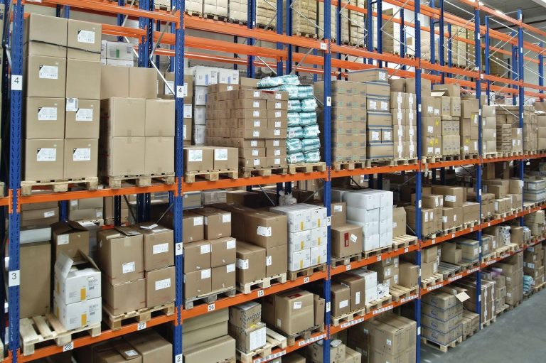 Regalprüfungen nach DIN 15635 health & safety ehrl Mit Paketen beladenes Palettenregal in einer Lagerhalle.